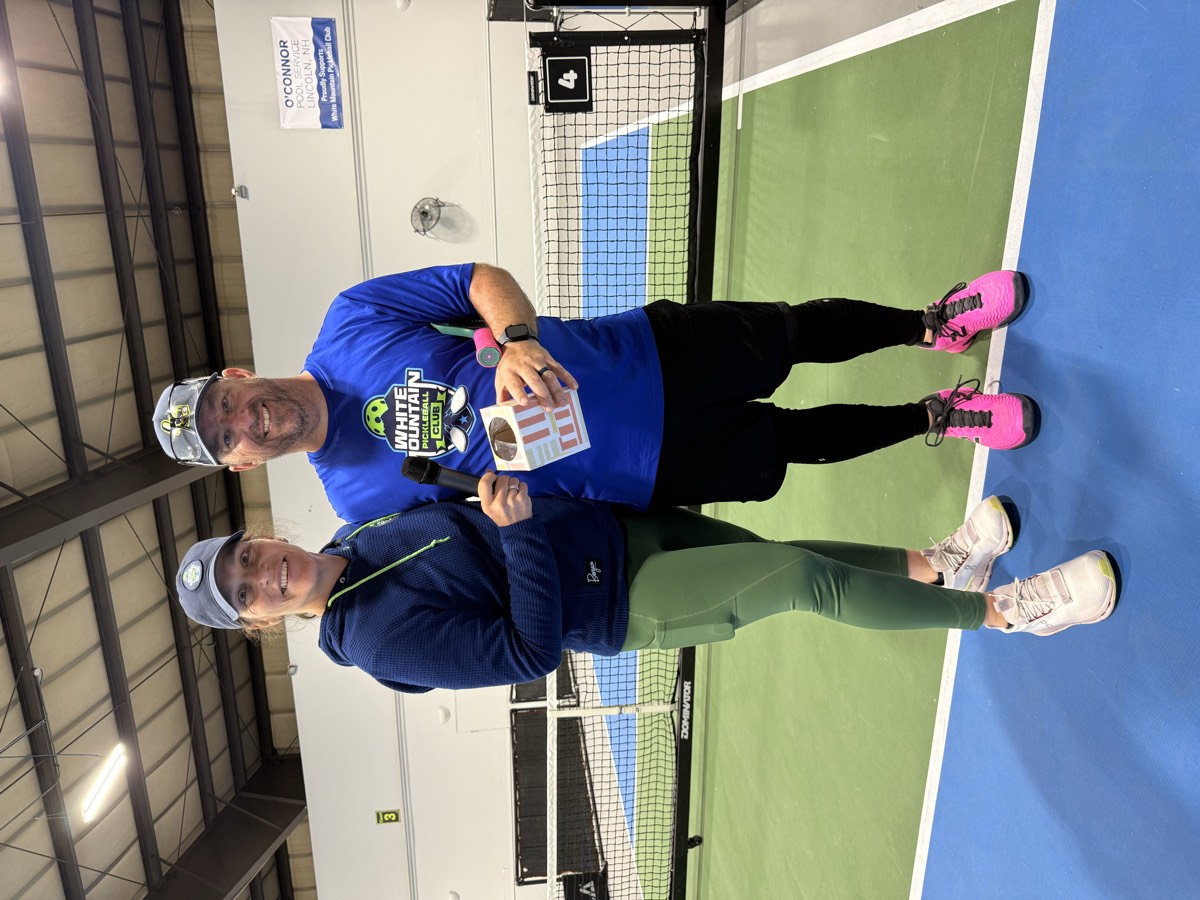 Two members in White Mountain Pickleball Club shirts courtside
